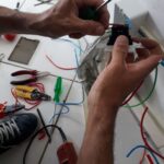 Eletricista fazendo ligação de cabos em uma tomada