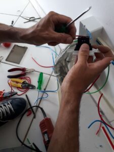 Eletricista fazendo ligação de cabos em uma tomada